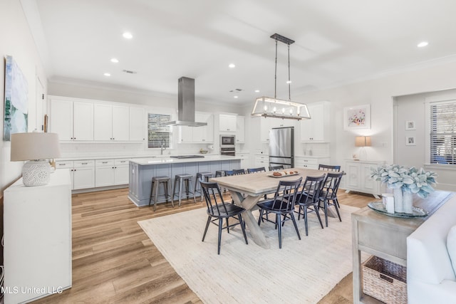 dining space with light hardwood / wood-style floors and ornamental molding