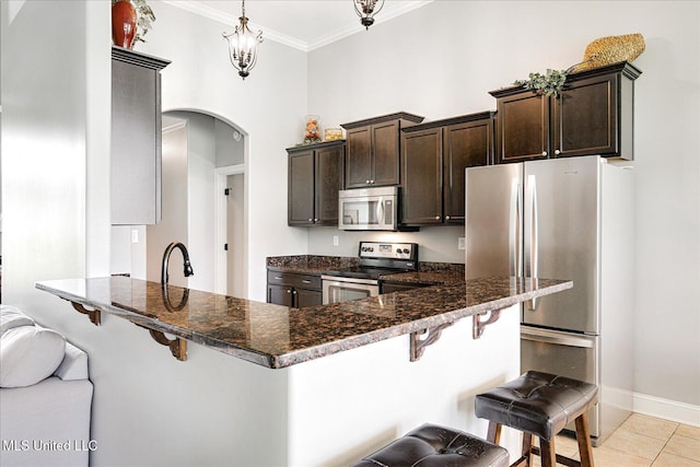 6865 Payne Ln, Olive Branch, MS 38654 - kitchen featuring stainless steel appliances, arched walkways, dark brown cabinetry, a kitchen bar, and crown molding