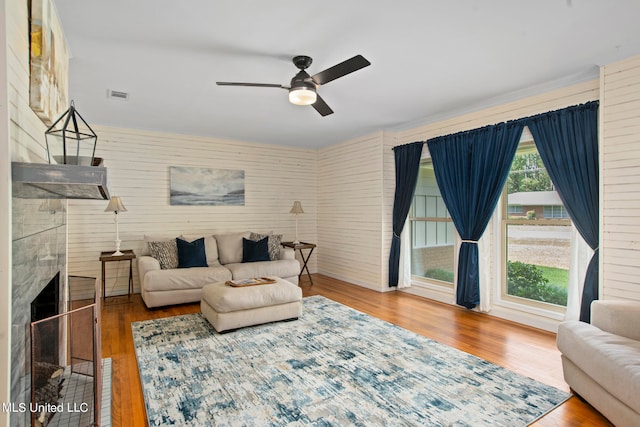 living room with ceiling fan, wood-type flooring, and a premium fireplace