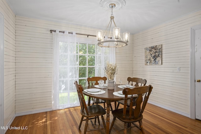 dining area featuring a notable chandelier, hardwood / wood-style floors, and wood walls