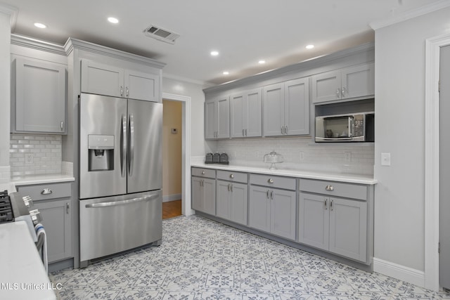 kitchen with backsplash, stainless steel appliances, crown molding, and gray cabinets