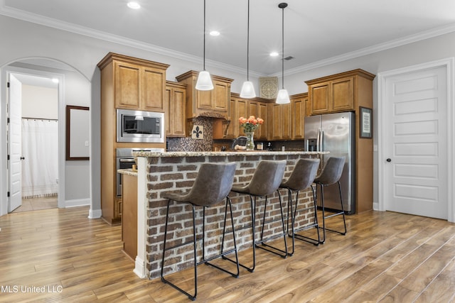 14463 Aerie Rd, Gulfport, MS 39503 - kitchen featuring stainless steel appliances, arched walkways, light wood-style floors, a breakfast bar area, and recessed lighting