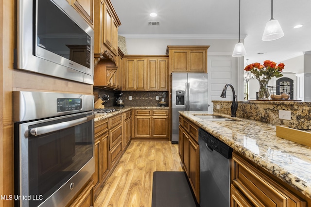 14463 Aerie Rd, Gulfport, MS 39503 - kitchen with stainless steel appliances, a sink, brown cabinets, ornamental molding, and light wood-type flooring