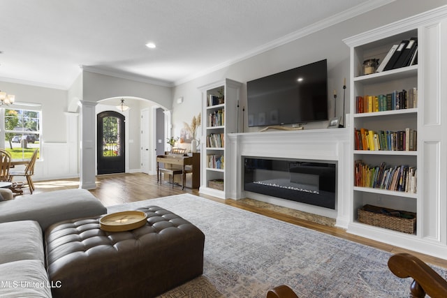 14463 Aerie Rd, Gulfport, MS 39503 - living room featuring arched walkways, decorative columns, ornamental molding, wood finished floors, and built in shelves