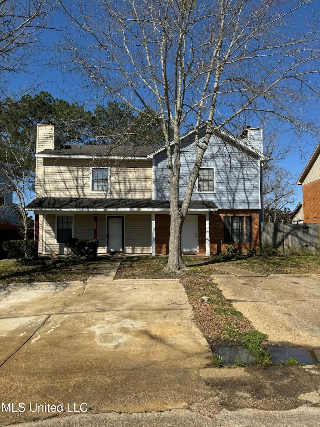 traditional-style house featuring a porch, fence, brick siding, and a chimney