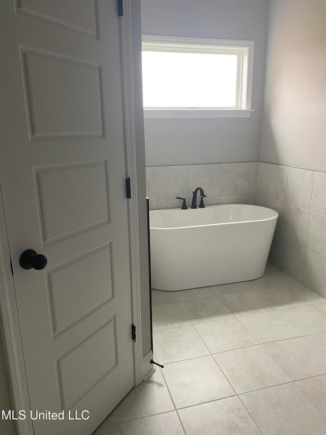 bathroom with tile patterned flooring, a bathtub, and tile walls