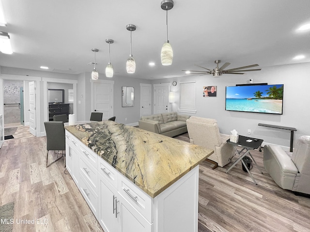 kitchen with open floor plan, white cabinets, and light wood-type flooring