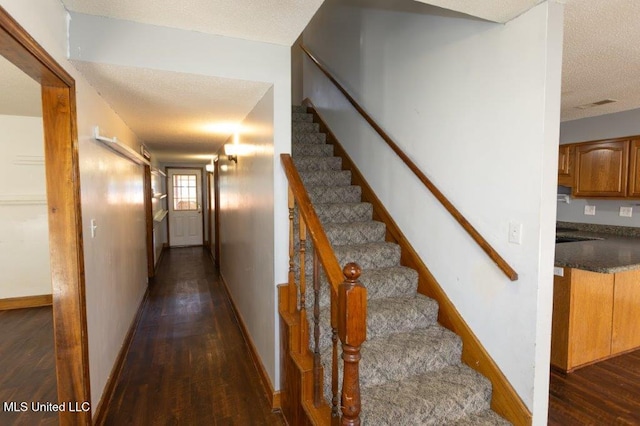 staircase featuring hardwood / wood-style flooring and a textured ceiling