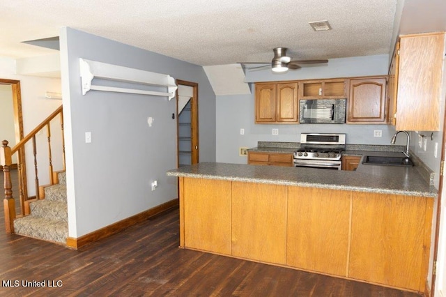 kitchen with gas stove, kitchen peninsula, a textured ceiling, dark wood-type flooring, and sink