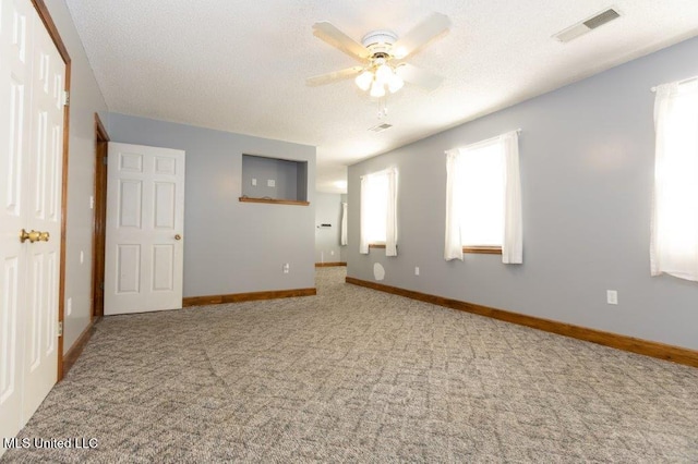 spare room with a wealth of natural light, carpet floors, and ceiling fan