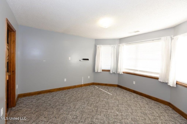 carpeted empty room featuring a textured ceiling