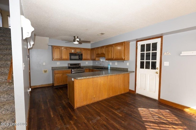 kitchen featuring kitchen peninsula, a textured ceiling, dark wood-type flooring, stainless steel range, and sink