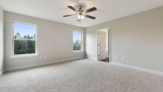 carpeted spare room with ceiling fan and baseboards