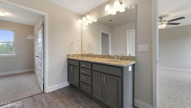 bathroom featuring ceiling fan, a sink, baseboards, and double vanity