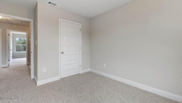 unfurnished bedroom with carpet floors, attic access, visible vents, and baseboards