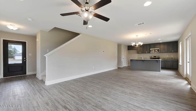 unfurnished living room featuring light wood-style floors, stairway, visible vents, and baseboards