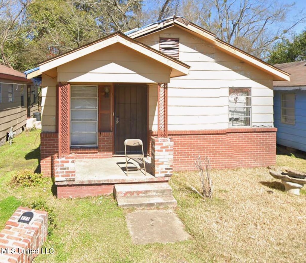 bungalow featuring covered porch and a front lawn