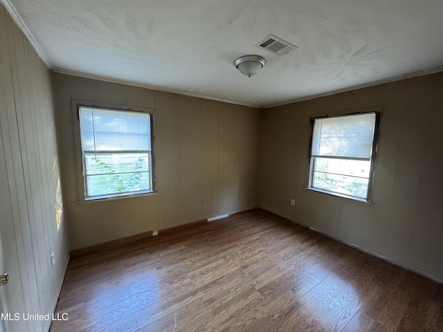 spare room with hardwood / wood-style flooring, wood walls, and ornamental molding