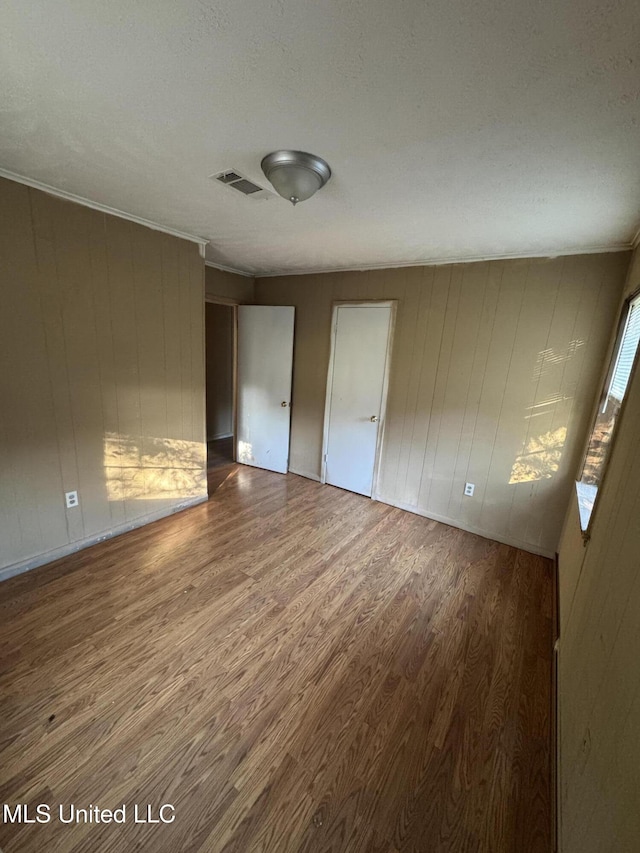 unfurnished bedroom featuring hardwood / wood-style flooring and wood walls