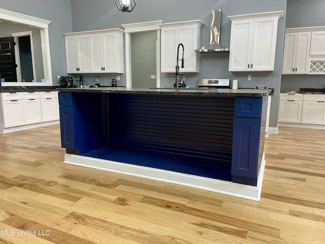 kitchen featuring white cabinets and wall chimney range hood