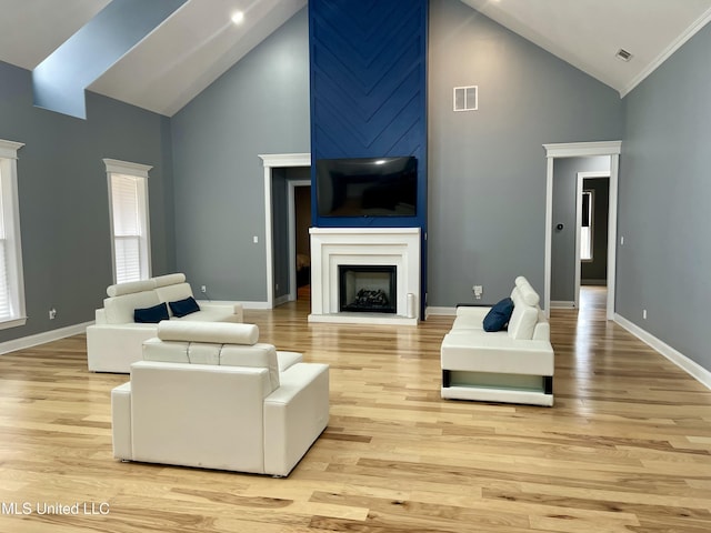 living room with high vaulted ceiling, a fireplace, and light hardwood / wood-style floors