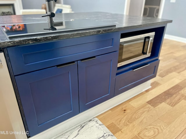 kitchen with blue cabinets and light hardwood / wood-style floors