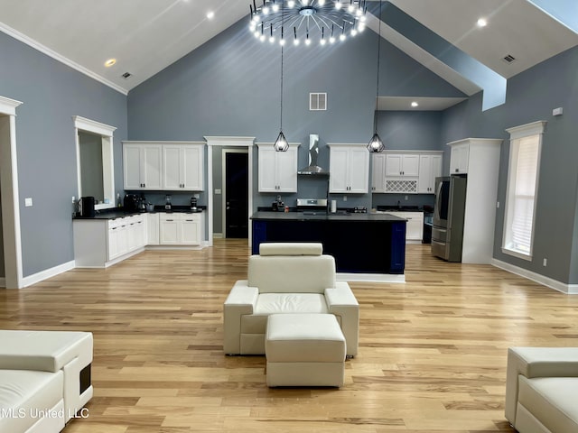 kitchen with pendant lighting, white cabinets, stainless steel refrigerator, and wall chimney exhaust hood