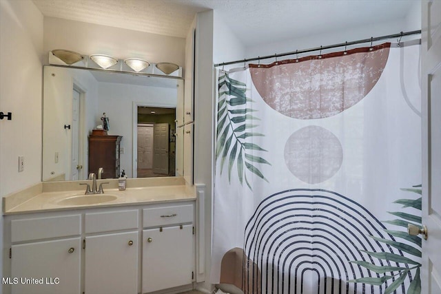 full bath with curtained shower, a textured ceiling, and vanity