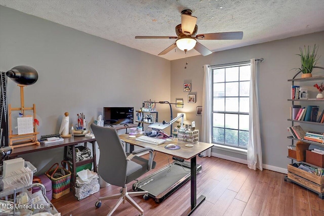 home office featuring plenty of natural light, a textured ceiling, ceiling fan, and wood finished floors