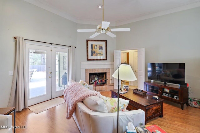 living room featuring light wood-type flooring, french doors, ornamental molding, and a ceiling fan