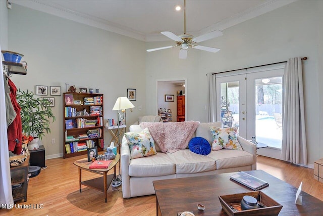 living area with ornamental molding, a ceiling fan, light wood-style flooring, french doors, and baseboards