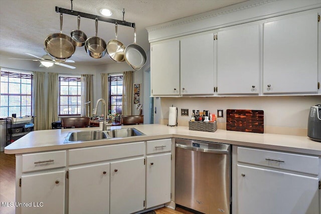 kitchen featuring a peninsula, ceiling fan, a sink, light countertops, and stainless steel dishwasher