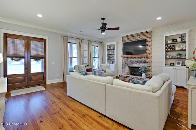 233 Arbor Trl, Brandon, MS 39047 - living room featuring wood finished floors, ornamental molding, a brick fireplace, a ceiling fan, and french doors