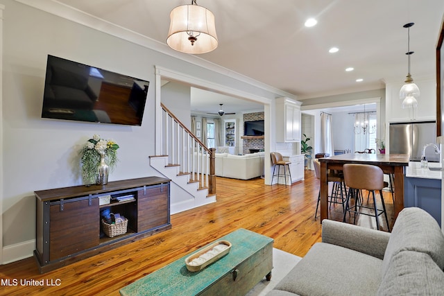233 Arbor Trl, Brandon, MS 39047 - living room featuring crown molding, light wood-type flooring, stairway, and ceiling fan with notable chandelier