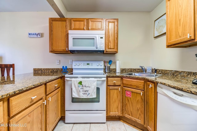 kitchen featuring light tile patterned flooring, white appliances, sink, and stone counters