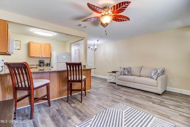 living room with ceiling fan with notable chandelier and light wood-type flooring