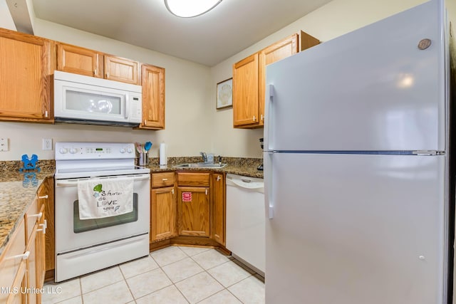 kitchen with stone counters, sink, light tile patterned flooring, and white appliances