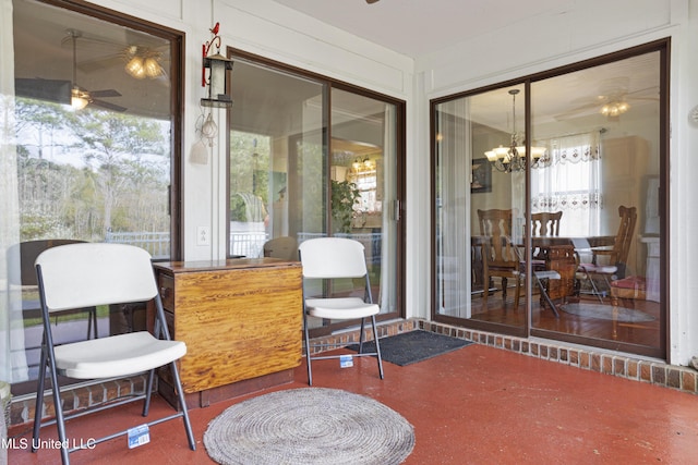 sunroom featuring ceiling fan with notable chandelier