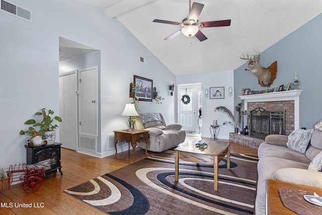 living room featuring a brick fireplace, ceiling fan, high vaulted ceiling, beamed ceiling, and light hardwood / wood-style floors