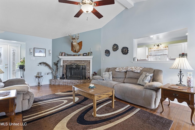 living room featuring vaulted ceiling with beams, ceiling fan, a fireplace, and wood-type flooring