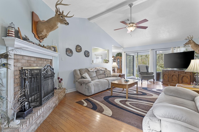 living room featuring high vaulted ceiling, ceiling fan, a fireplace, beamed ceiling, and light hardwood / wood-style floors