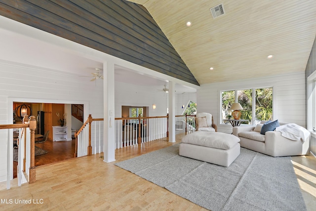 living room with wood walls, wood-type flooring, high vaulted ceiling, and wooden ceiling