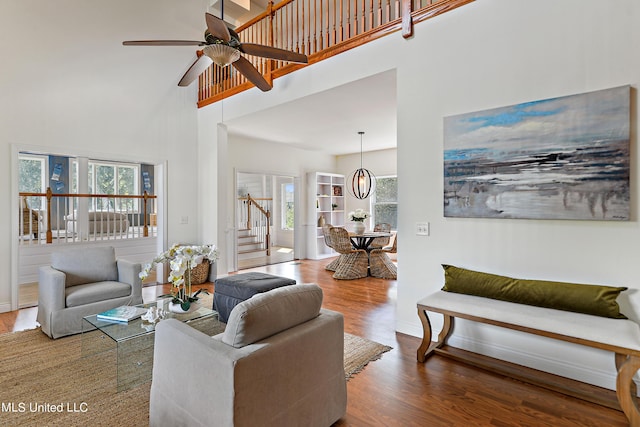 living room featuring ceiling fan, plenty of natural light, wood-type flooring, and a high ceiling