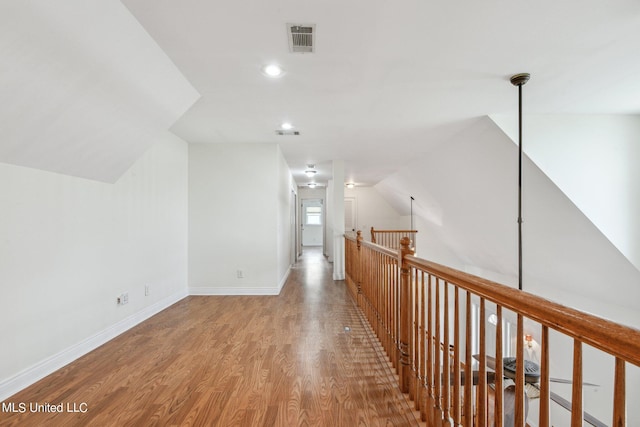 hallway with lofted ceiling and hardwood / wood-style floors