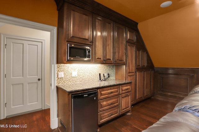 bar with stainless steel microwave, black dishwasher, dark wood-type flooring, light stone counters, and tasteful backsplash