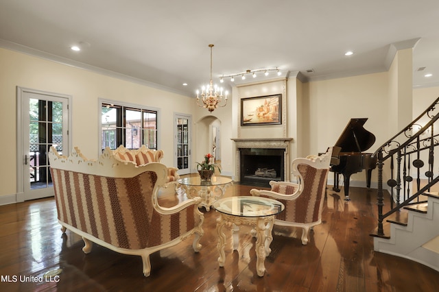 living room featuring dark wood-type flooring, a notable chandelier, and ornamental molding