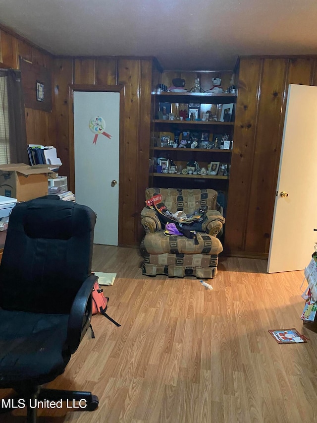 living area featuring light hardwood / wood-style floors and wooden walls