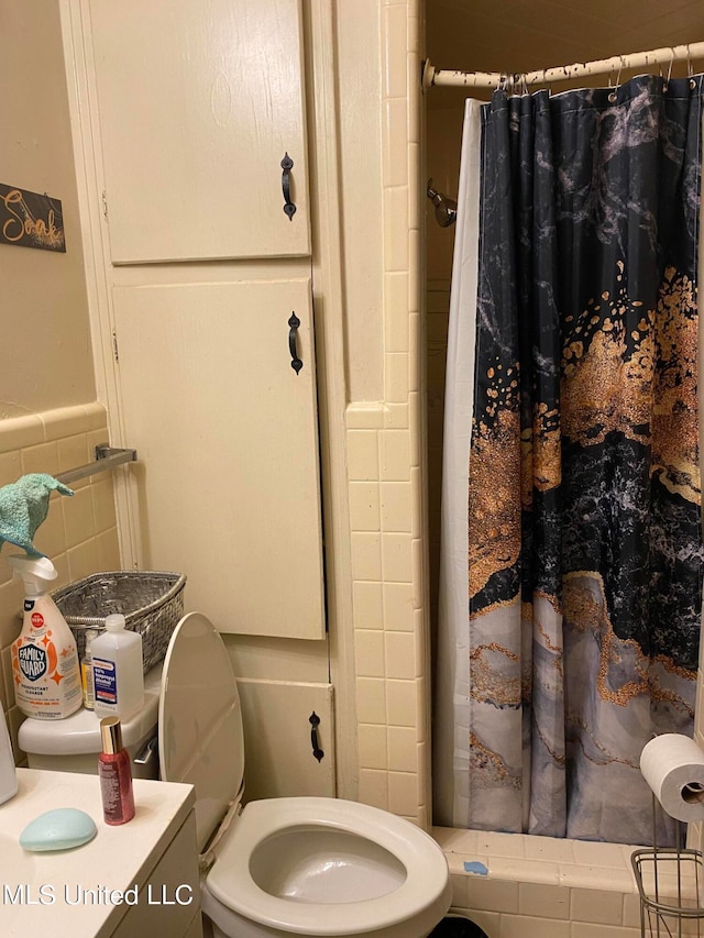 bathroom featuring tile walls, vanity, a shower with shower curtain, and toilet