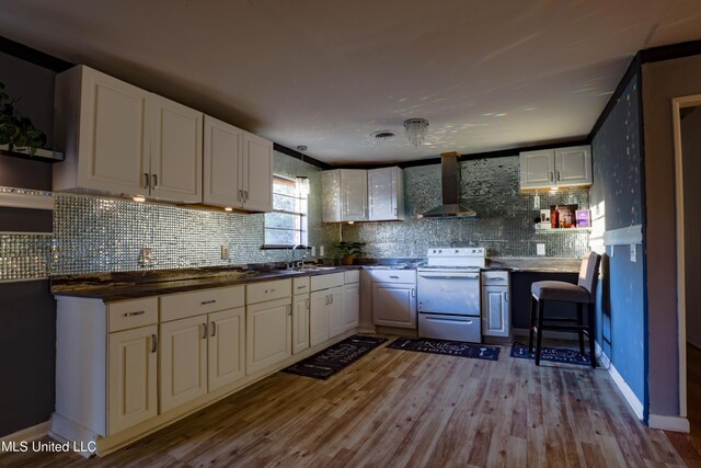 816 NE Boling St, Magee, MS 39111 - kitchen with white electric range, wall chimney exhaust hood, wood finished floors, and white cabinetry