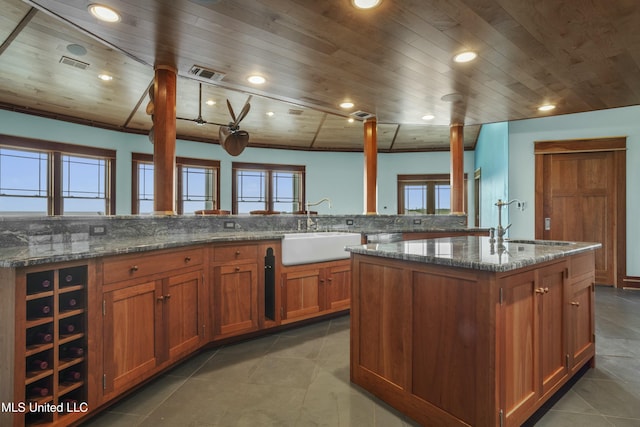 141 Janelle Dr, Bay Saint Louis, MS 39520 - kitchen with a sink, wood ceiling, a kitchen island with sink, brown cabinets, and dark stone countertops